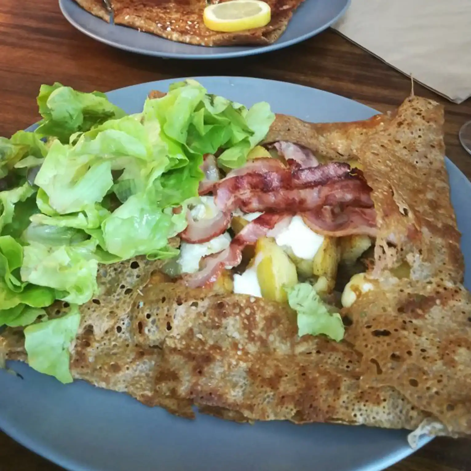 La Gouel est La Spécialité de la Crêperie du Frugy, la plus vendue ! Cette crêpe de sarrasin est composée de fromage Petit Lorientais - bio et breton, pomme de terre, poitrine fumée, oignons frais cuisinés au cidre kerné, crème épaisse, salade, vinaigrette.